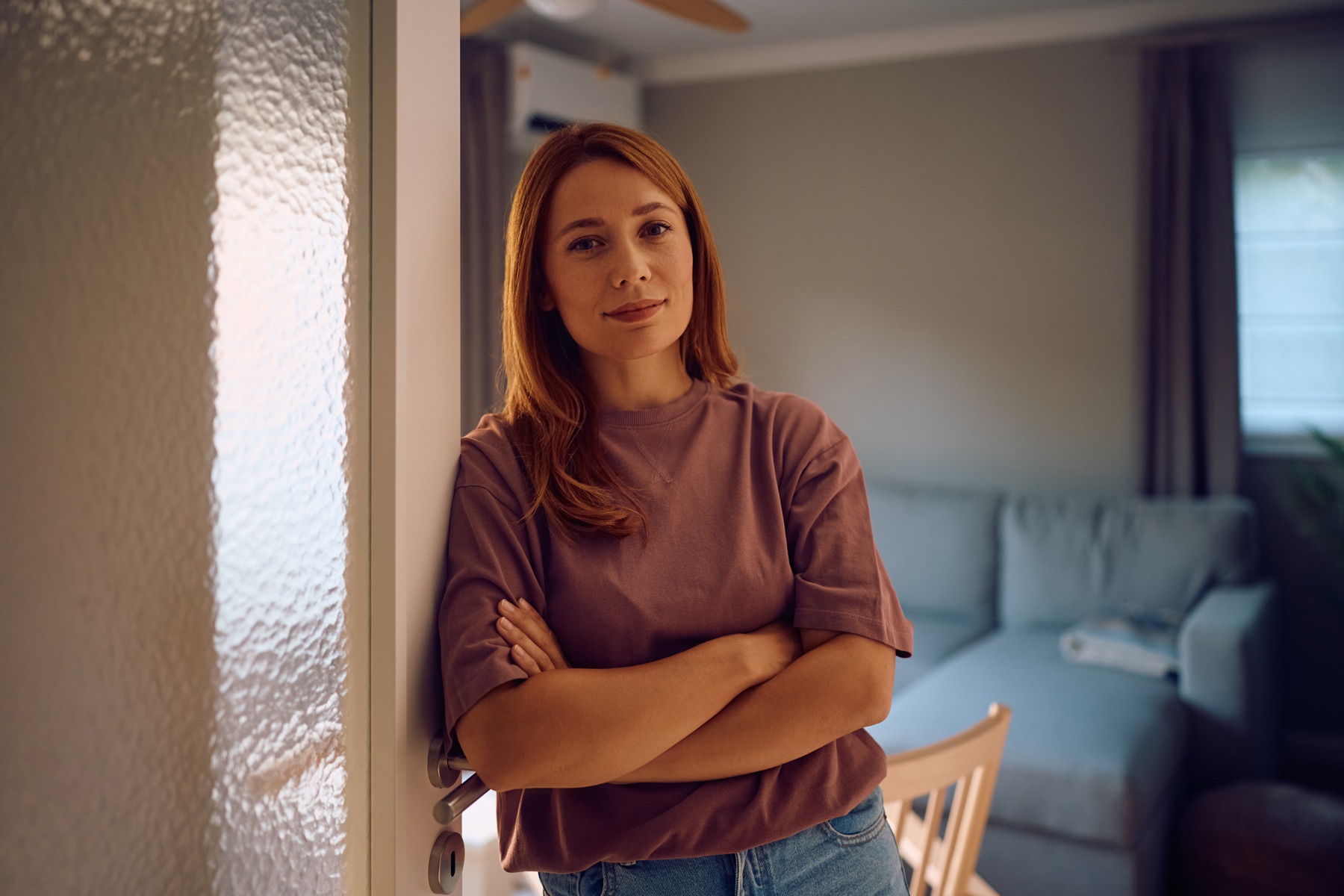 Mujer joven en su casa, brazos cruzados, mirada serena
